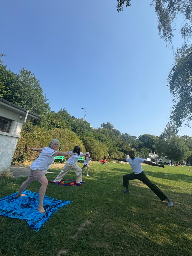 Séance de mouvement en plein air : un petit groupe en posture de yoga sur une pelouse.