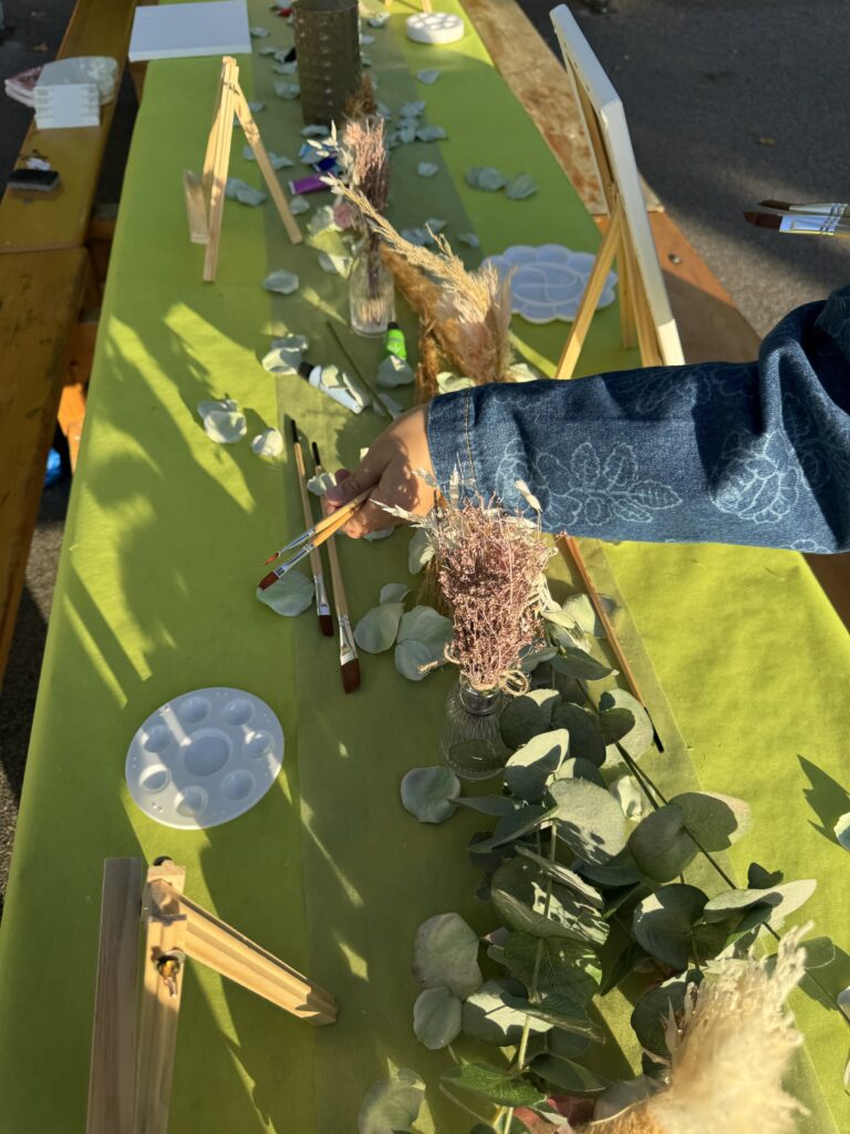 Table d’atelier décorée de feuillages d’eucalyptus, avec chevalets, pinceaux et palettes.