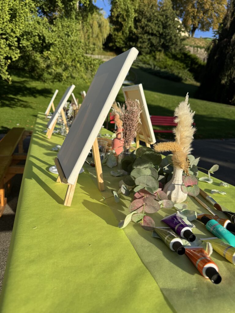 Chevalets, tubes de peinture et fleurs séchées sur la table de l’atelier.