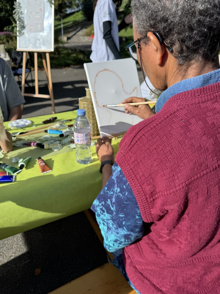 Une participante, vue de dos, commence à peindre sur sa toile.