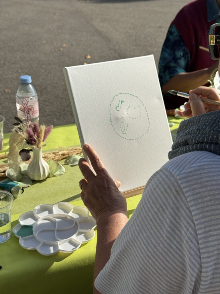 Une participante tient sa toile, où apparaît une première esquisse.