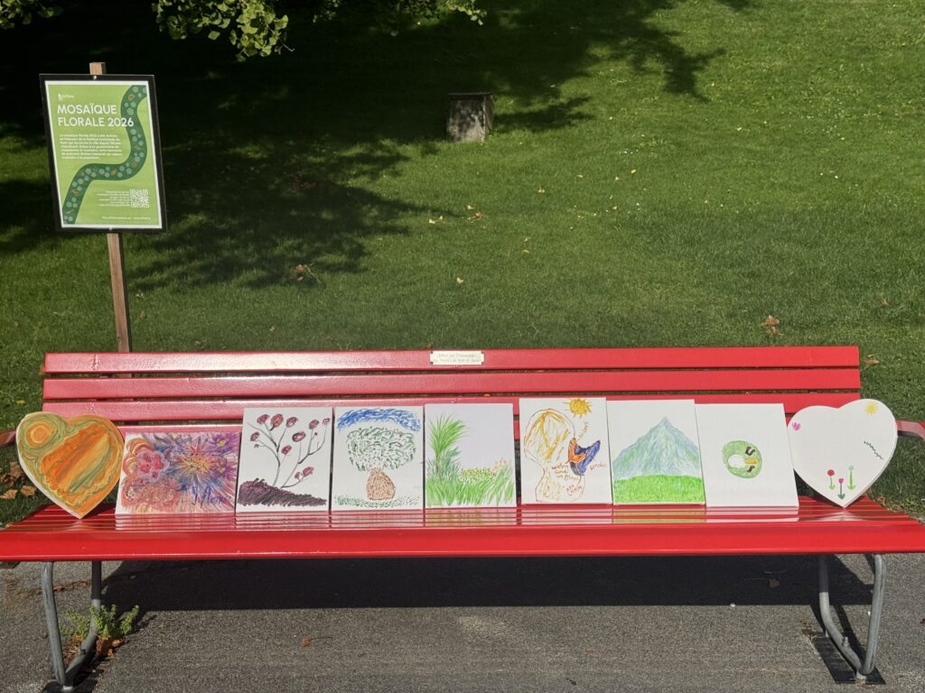 Les toiles peintes pendant l’atelier, alignées sur un banc rouge dans un parc.