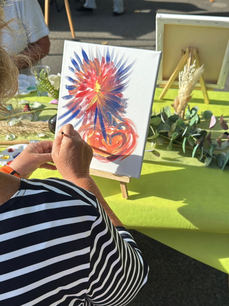 Une participante peint une fleur rouge et bleue sur une toile.